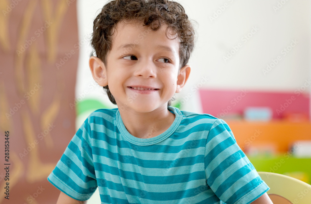 Fototapeta premium Portrait of cute caucasian boy smiling in classroom school, Happy white american boy kid in kindergarten, elementary classroom, Pre school kid education concept