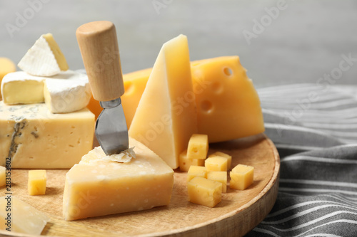 Different types of delicious cheese in wooden plate, closeup