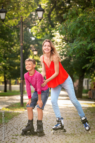 Fototapeta Naklejka Na Ścianę i Meble -  Mother and son roller skating in summer park