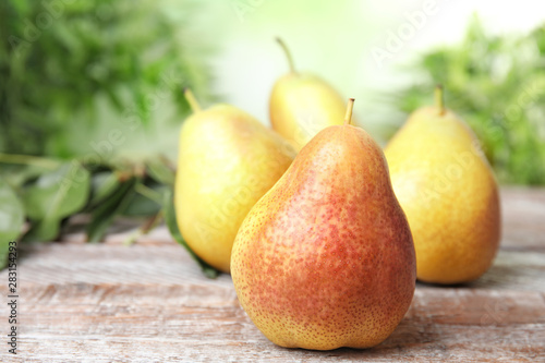 Ripe juicy pears on brown wooden table against blurred background. Space for text