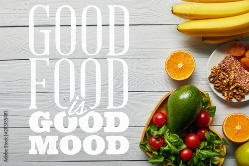 top view of fresh fruits, vegetables in heart-shaped bowl on wooden white background with good food is good mood lettering