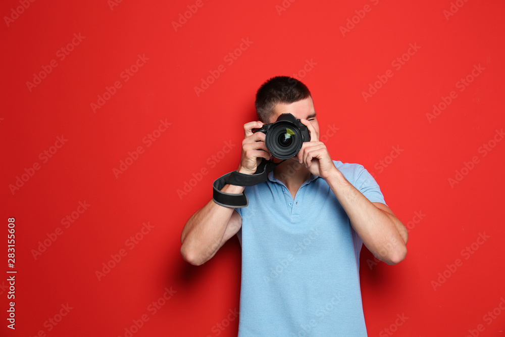 Young professional photographer taking picture on red background Young professional photographer taking picture on red background
