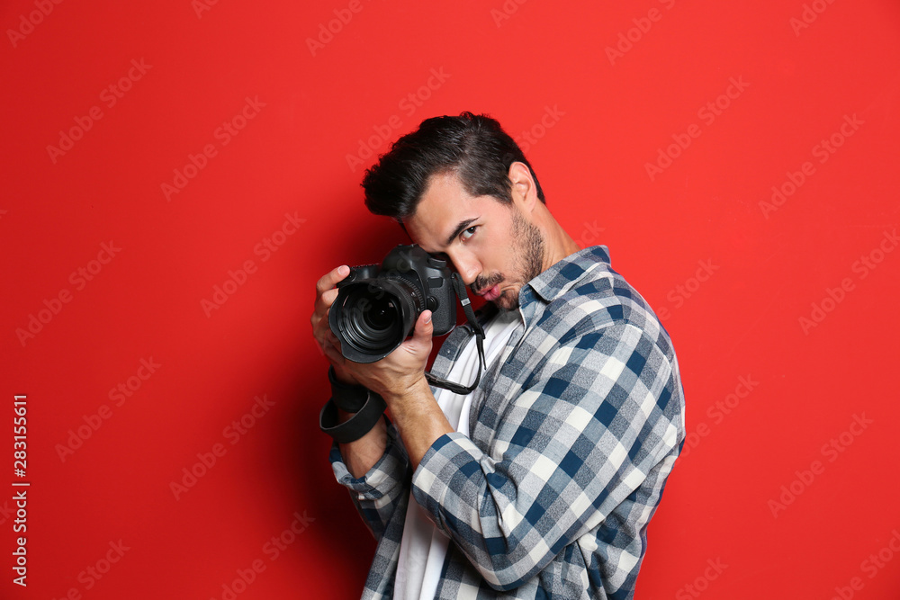 Emotional photographer with professional camera on red background Emotional photographer with professional camera on red background