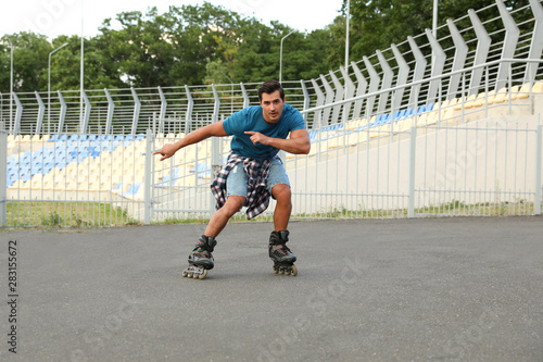 Handsome young man roller skating outdoors. Recreational activity