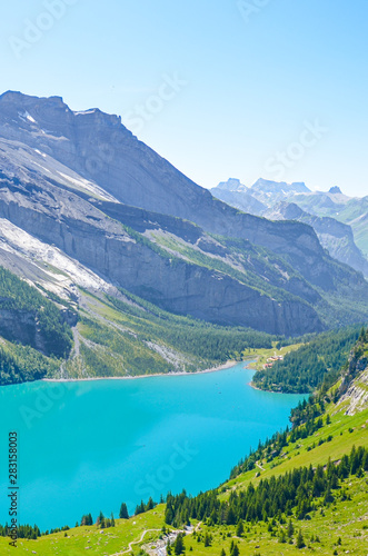 Vertical picture of amazing Oeschinensee, Oeschinen Lake, in Swiss Alps by Kandersteg. Turquoise lake with mountains and rocks in background. Switzerland summer. Tourist destinations