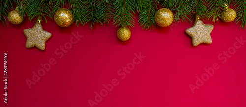 Christmas border. Fir branches and ornament on red background with copy space for your text. Christmas greeting card. Winter xmas holiday theme. Happy New Year.