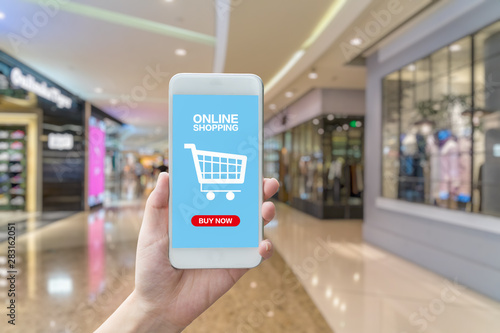 Smart phone online shopping in woman hand. Shopping center in background.