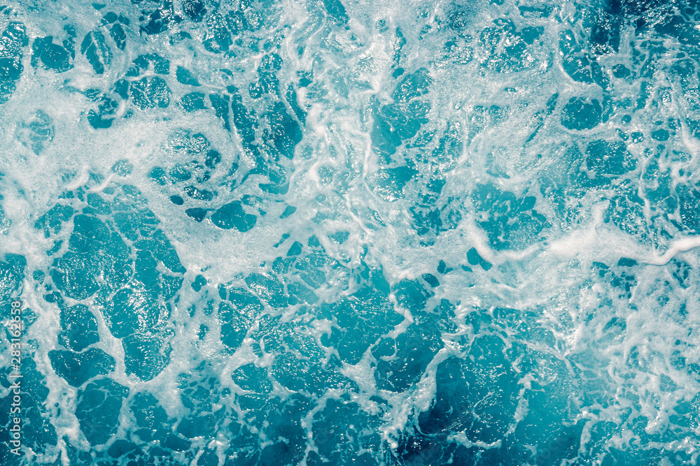 Pale blue green sea surface with waves and foam, abstract background