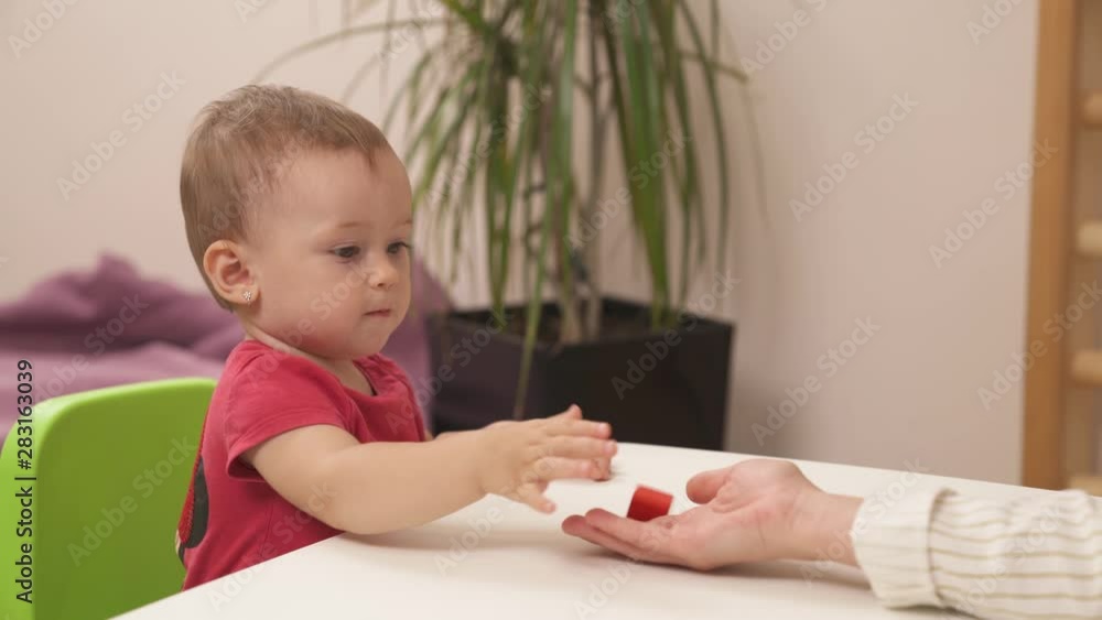 Close-up demonstration video of kids fine motor skills development session. Toddler girl giving wooden blocks to a teacher. Sensory playful exercises