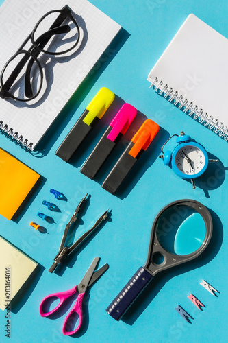back to school or office styled scene with multicolored school supplies on blue , back to school conceptual background flat lay.