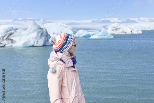 Adventure traveller woman visiting nature landscape in summer near the glacier on Iceland, wearing hat and colorful coat