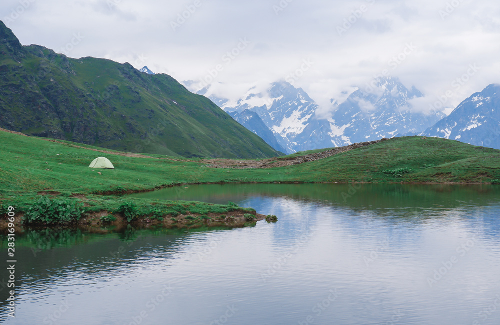green tent on the background of mountains, tent near the lake, camping in the mountains, beautiful nature and landscape