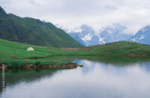 green tent on the background of mountains, tent near the lake, camping in the mountains, beautiful nature and landscape