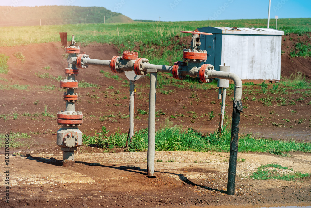 Oil and gas processing plant with pipe line valves. Oil pipeline valves in the oil and gas industry. Valve plug an oil pipeline in the field on a sunny summer day. Oil and gas processing plant with pipe line valves. Oil pipeline valves in the oil and gas industry. Valve plug an oil pipeline in the field on a sunny summer day.