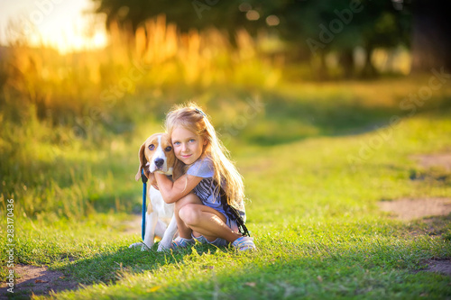 Obraz na płótnie cute girl walks with her beagle puppy in the park at sunset, best friend w salonie