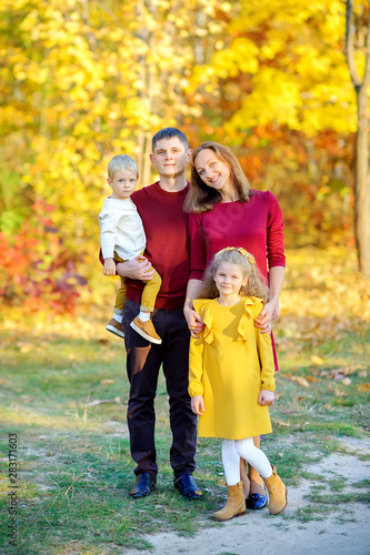 Happy family resting in a beautiful autumn park on a background of bright foliage