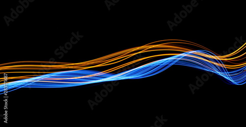 Long exposure, light painting photography.  Vibrant streaks of electric blue and metallic gold color, against a black background. © LizFoster