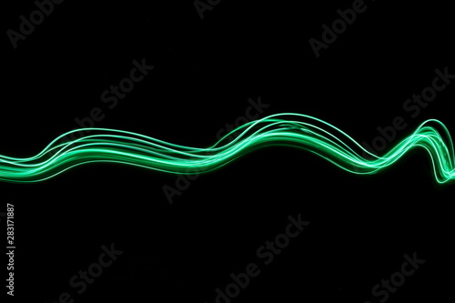 Long exposure, light painting photography.  Vibrant abstract streaks of neon green color against a black background.
