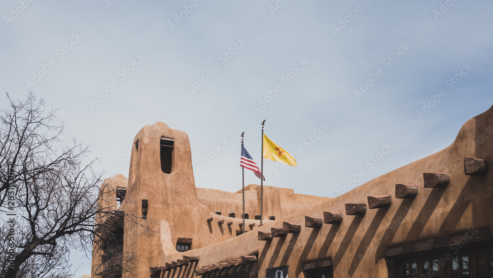 Fototapeta premium Flags over pueblo style building in Santa Fe, NM, USA