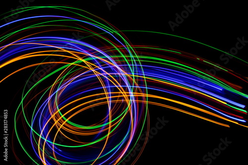 Long exposure, light painting photography. Vibrant streaks of neon multi color against a black background. © LizFoster