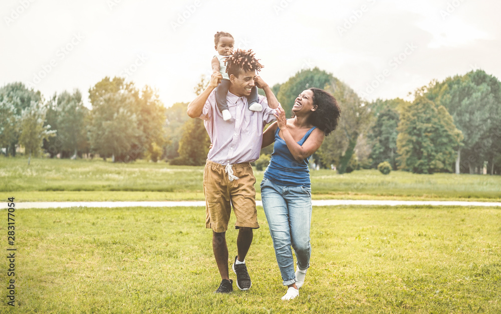 Happy black family having fun doing picnic outdoor - Parents and their daughter enjoying time together in a weekend day - Love tender moment and happiness concept - Focus on father and mother on faces