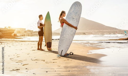 Canvas Print Surfers couple waiting for the high waves on beach - Sporty people with surf boa