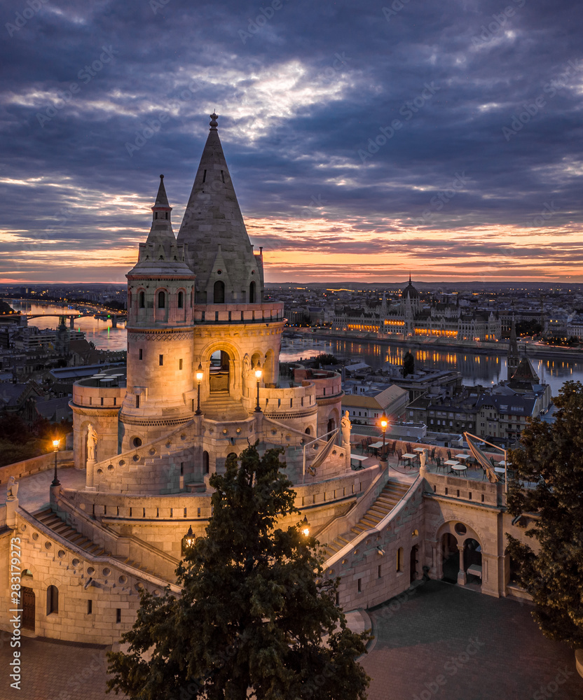 Budapest, Hungary - The main tower of the famous Fisherman's Bastion (Halaszbastya) from above with Parliament building and River Danube at background at sunset,sunrise,blue hour, night