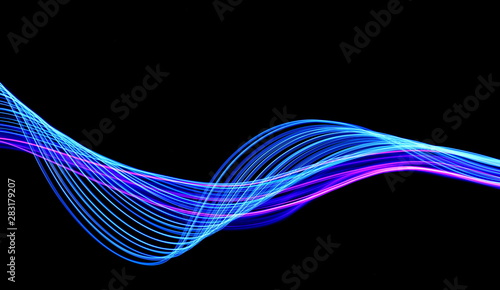 Long exposure, light painting photography.  Vibrant streaks of neon blue and pink color against a black background.