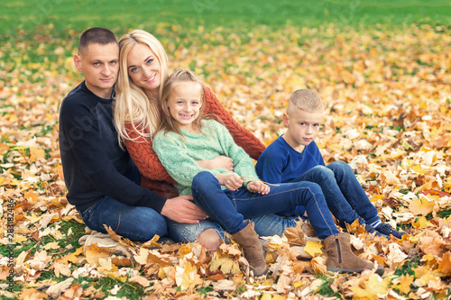 Happy family resting in beautiful autumn park. Parents with two children in autumn leaf.