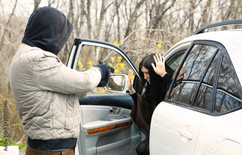 a thief with a gun threatens a woman driver