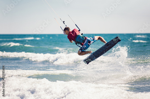 Professional kiter makes the difficult trick on a beautiful background. Kitesurfing Kiteboarding action photos man among waves quickly goes