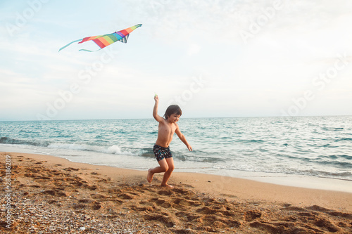Little boy playing with kite on tropical beach. Summer vacation concept, child playing on sandy beach
