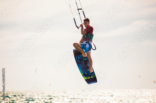 Professional kiter makes the difficult trick on a beautiful background. Kitesurfing Kiteboarding action photos man among waves quickly goes