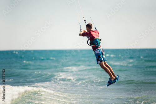 Professional kiter makes the difficult trick on a beautiful background. Kitesurfing Kiteboarding action photos man among waves quickly goes