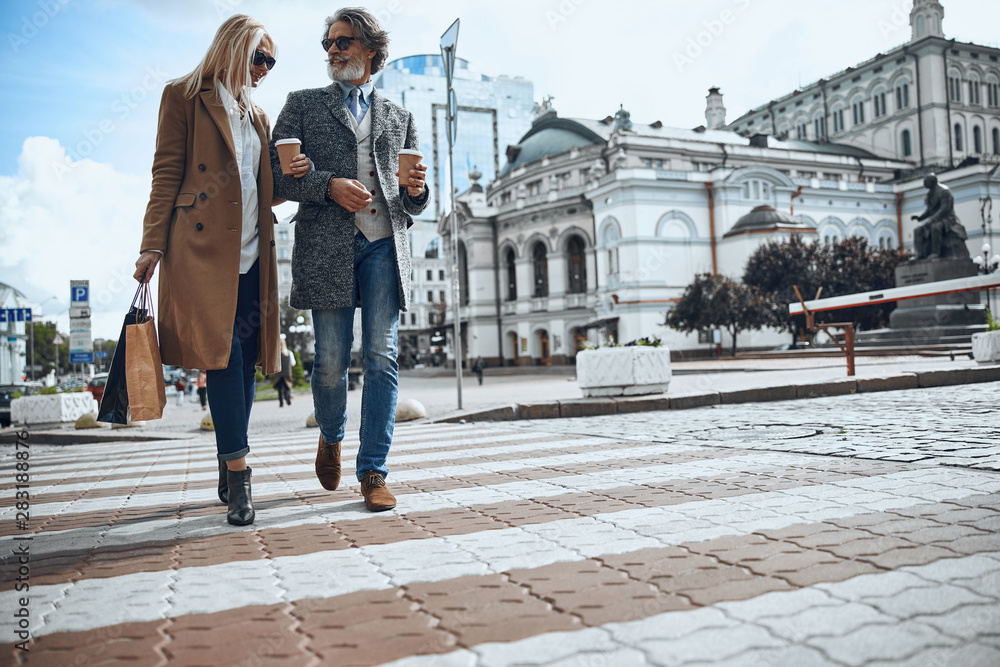 Smiling mature couple crossing the road stock photo