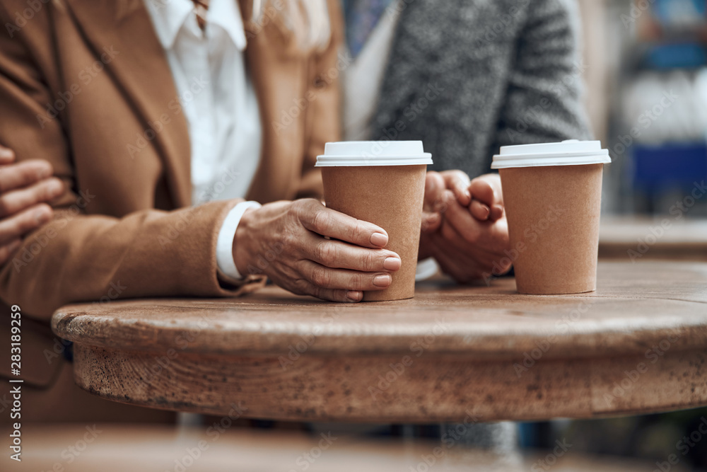 Hands holding carton cups of coffee on the table stock photo Hands holding carton cups of coffee on the table stock photo