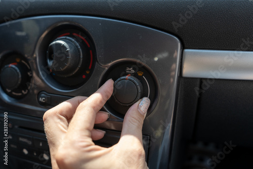 Woman hand switches the air conditioner modes on the panel in the car