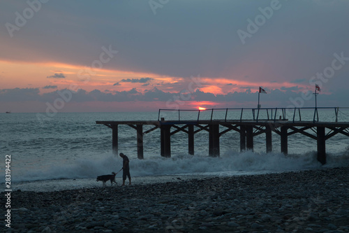 sun setting over Batumi beach Dock  as powerful waves roll in  and a very colorful sky is reflected on the beach