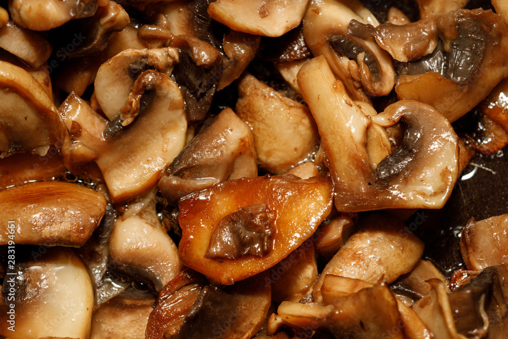 Fried champignon mushrooms in a pan closeup background texture Fried champignon mushrooms in a pan closeup background texture