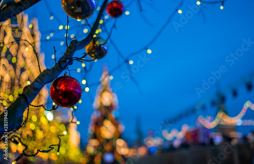 Christmas lights on the tree trunk, closeup. Blurred background city street with Christmas illuminations. Christmas and New Year holiday background. Vintage color tone. Copy space for your text.