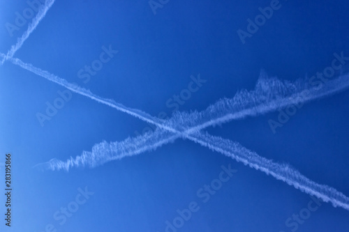 Trace of the plane in the blue sky. Sunny day. Greece. Concept- travel, vacation, geoengineering and chemtrails.