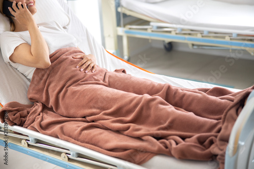 Smiling lady talking on cellphone in hospital room