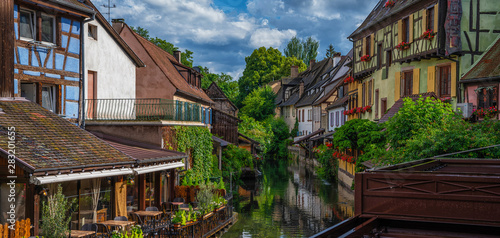 Colmar, Alsace, France. Water canal and traditional half timbered houses. Beautiful view of the historic town with tourists taking a boat ride along traditional colorful houses on idyllic river.