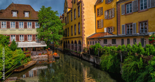 View of the historic town of Colmar, also known as Little Venice, with tourists taking a boat ride along traditional colorful houses on idyllic river Lauch, Colmar, Alsace, France