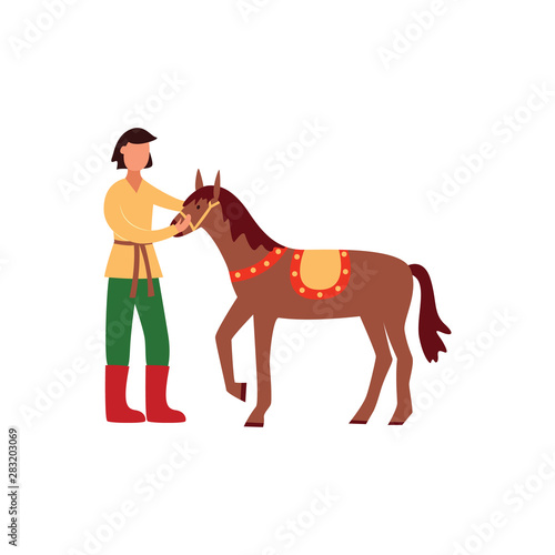 Brunet young gypsy man in traditional pants and shirt holds and strokes his horse.