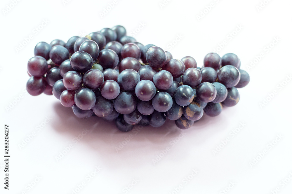 A claster of purple grapes on pink background