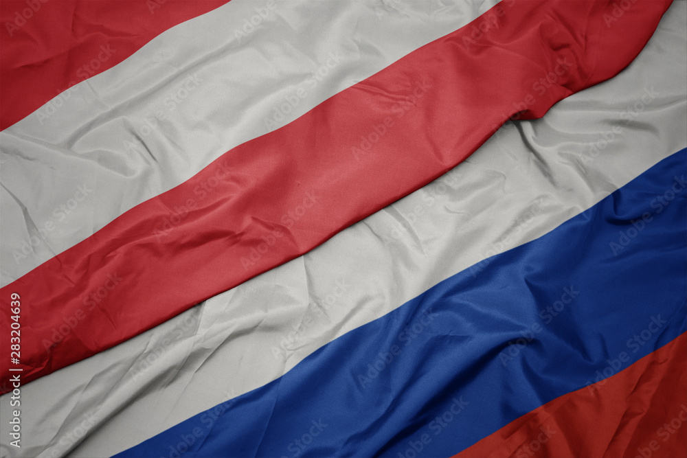 waving colorful flag of russia and national flag of austria. waving colorful flag of russia and national flag of austria.