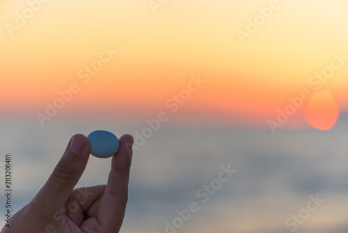stone pebble in the hand of a man on sunset background