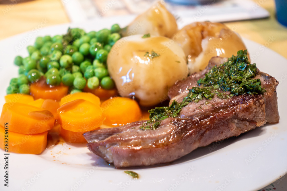A dinner of lamb chop with boiled potatoes, peas and carrots. A dinner of lamb chop with boiled potatoes, peas and carrots.