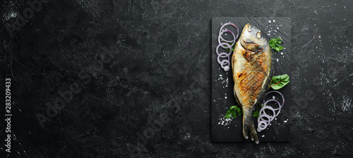 Dorado fish grilled on stone plate. Top view. Free copy space.